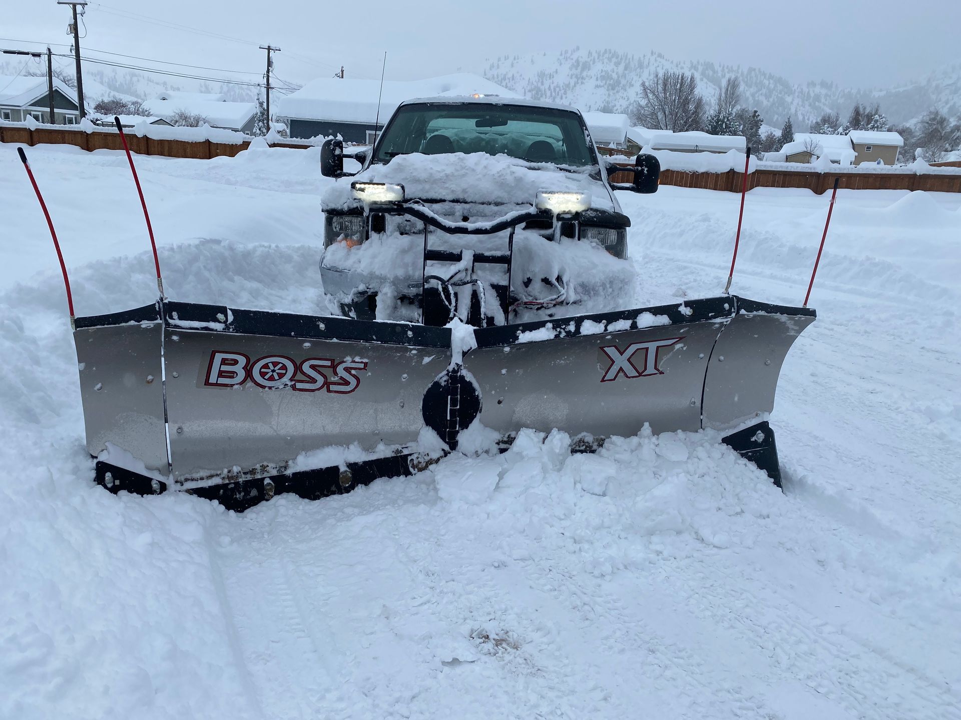 A truck with a snow plow attached to it is parked in the snow.