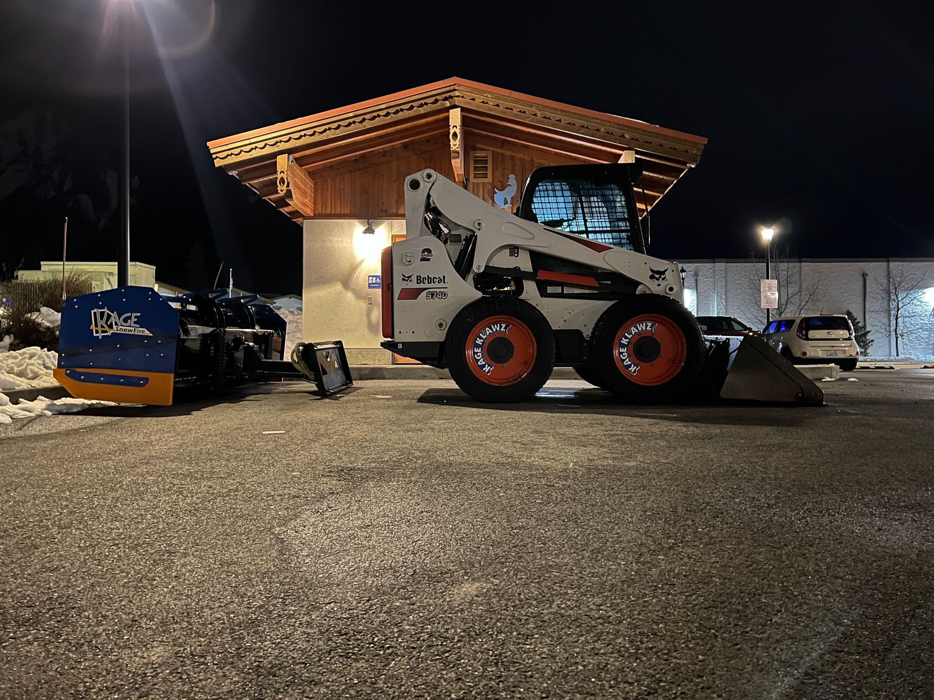 A bobcat is parked in front of a building at night.