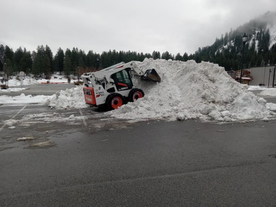A bobcat is clearing snow from a parking lot