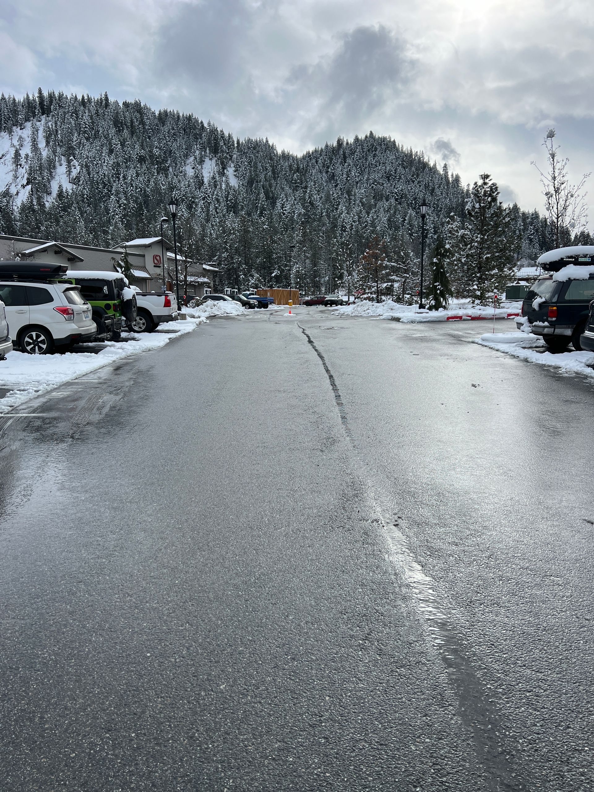 A snowy street with cars parked on the side of it