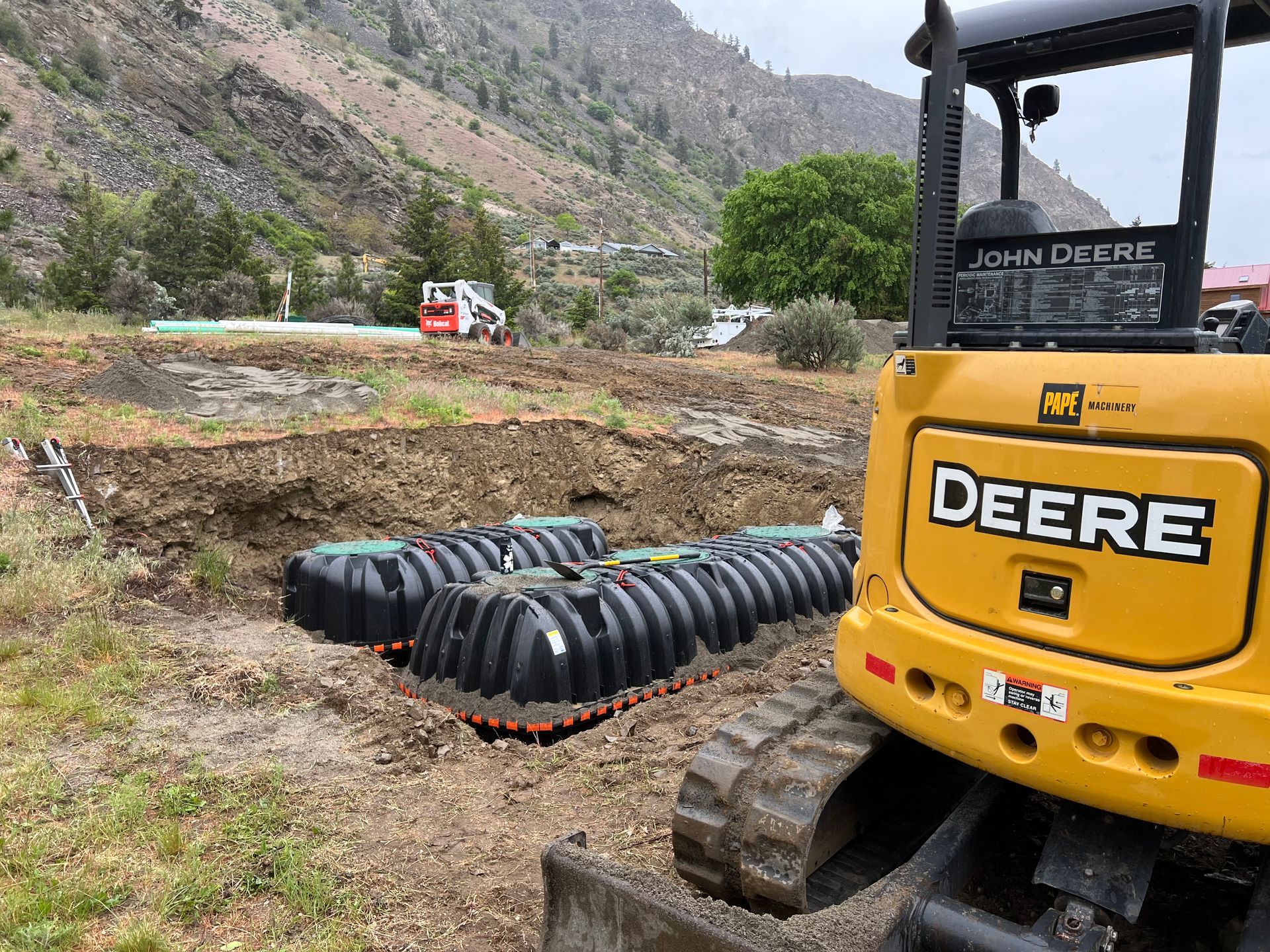 A yellow deere bulldozer is parked in a dirt field.