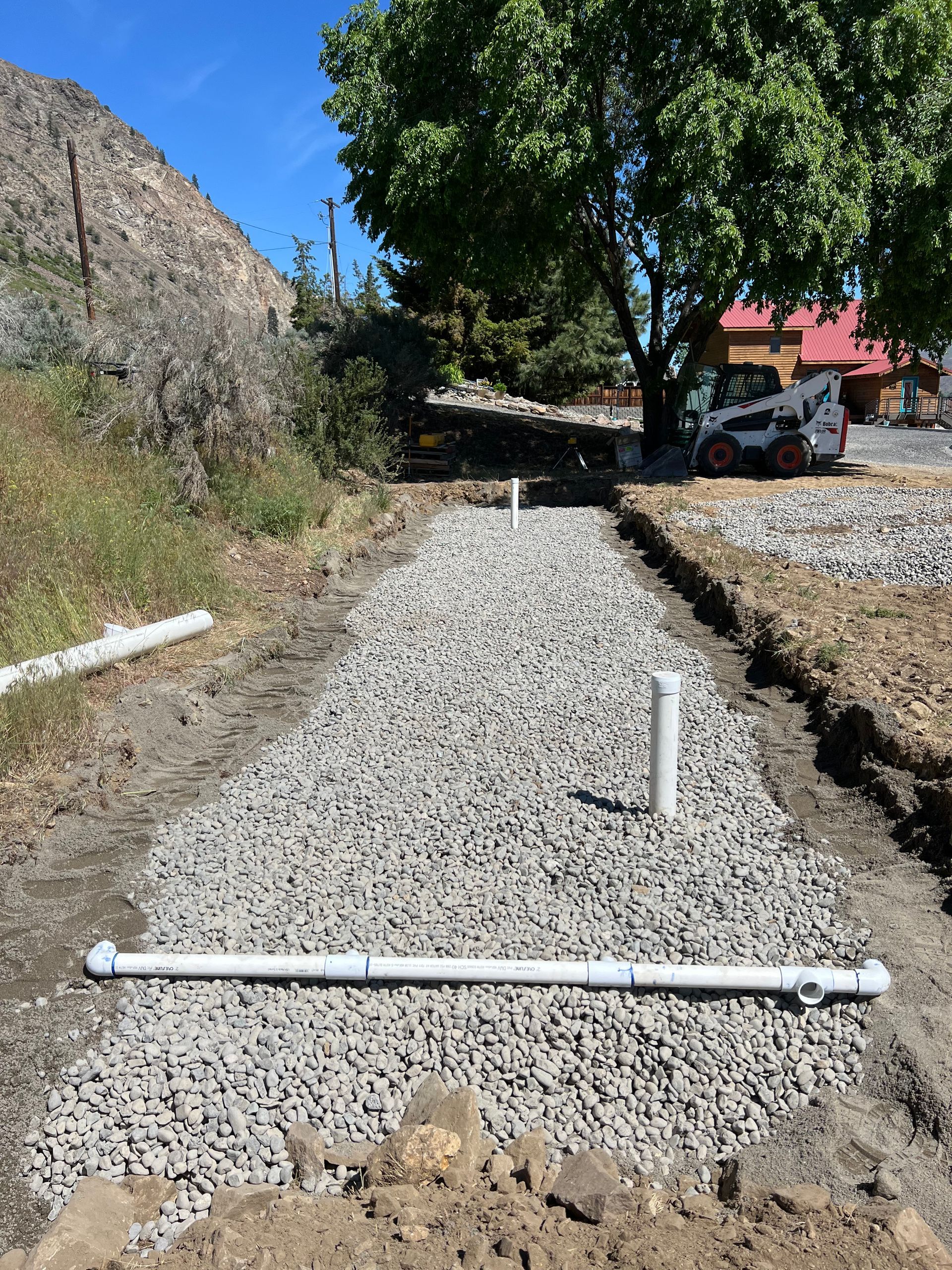 A white pipe is sitting on top of a gravel road.