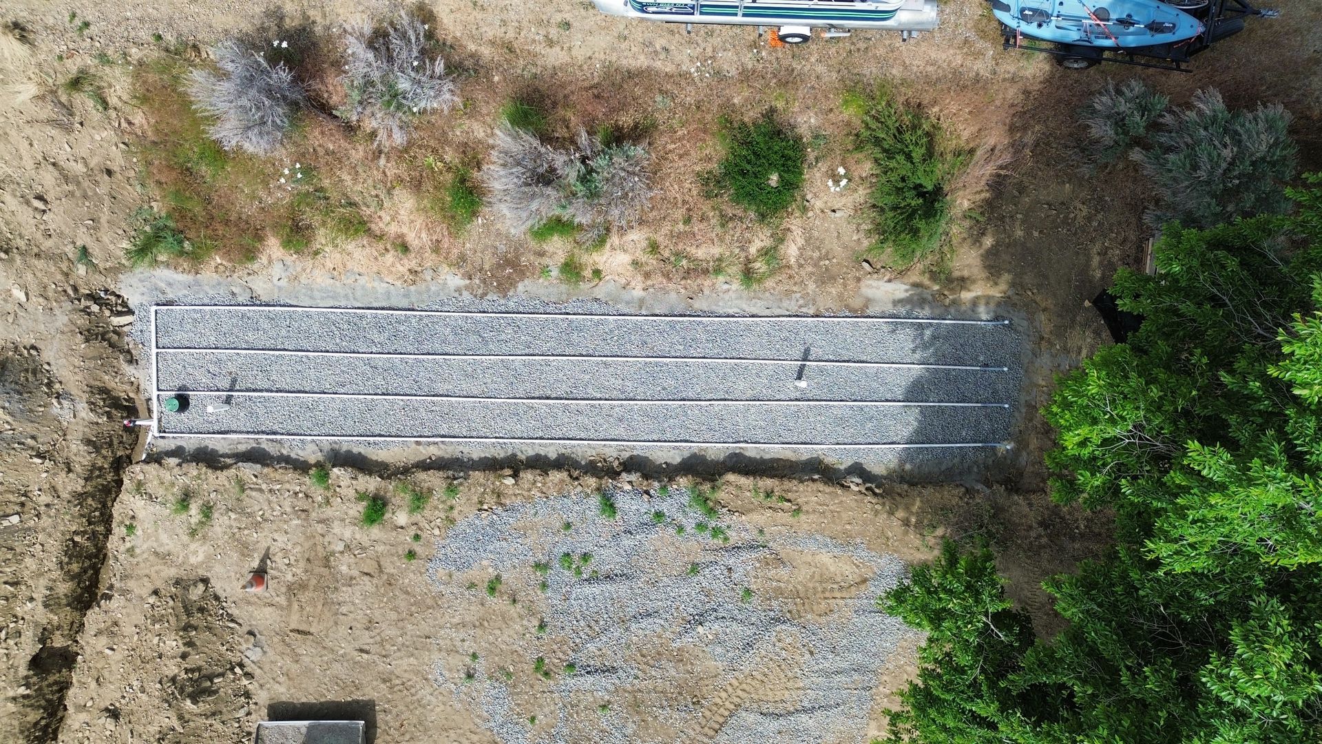 An aerial view of a graveyard surrounded by trees and dirt.