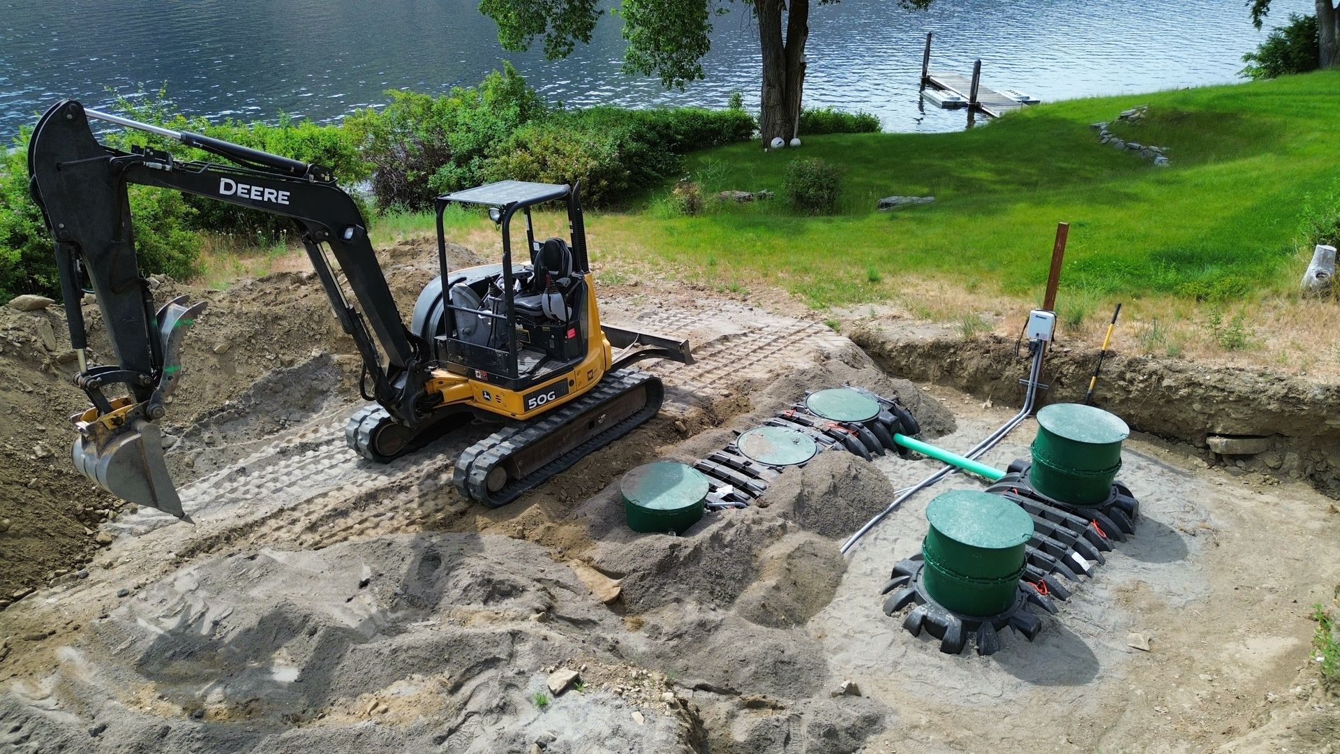 An excavator is digging a hole in the ground next to a lake.