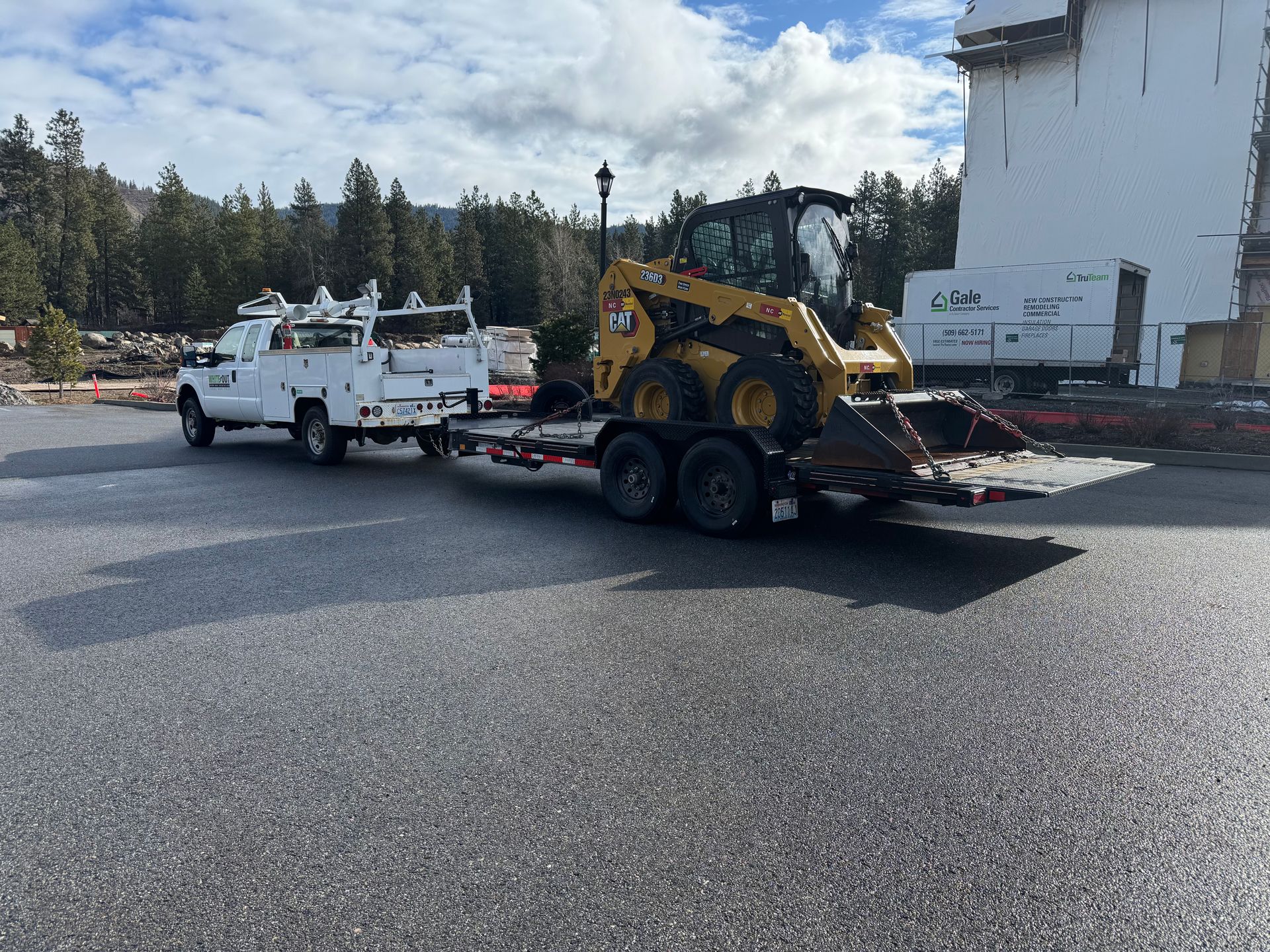 A white truck is towing a bulldozer on a trailer.