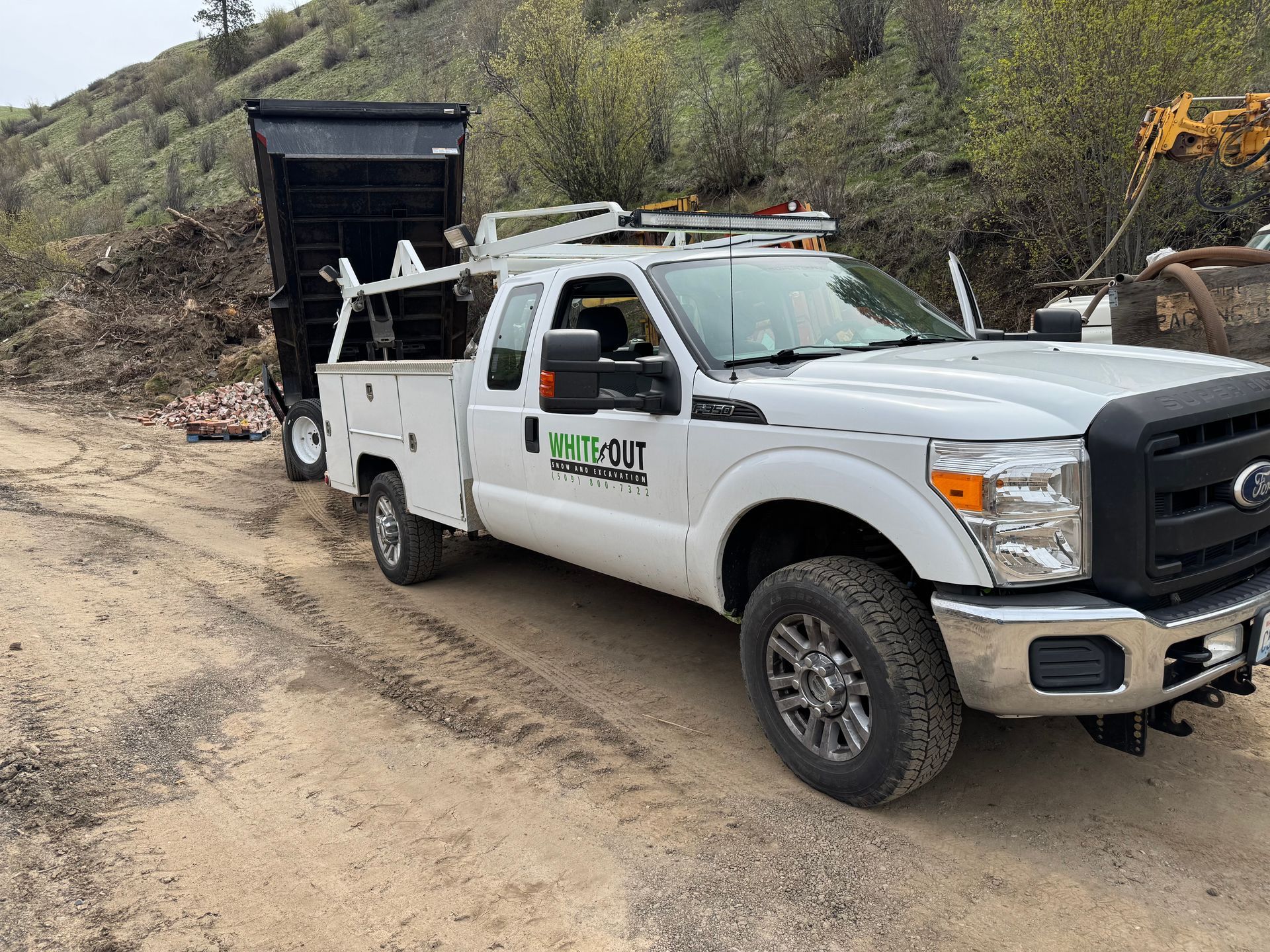 A white truck is parked on the side of a dirt road.