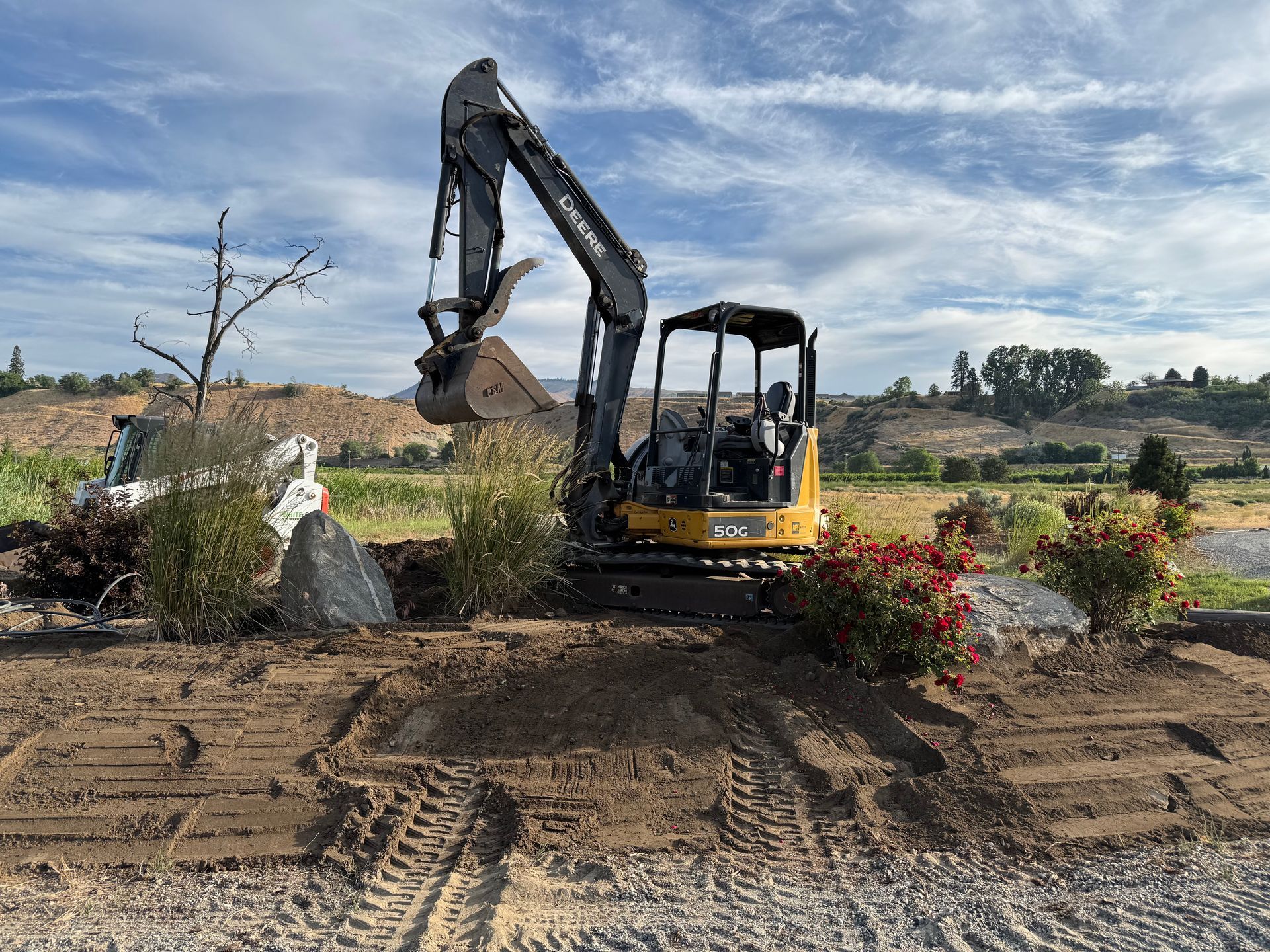 A small excavator is digging a hole in a dirt field.