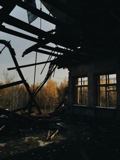 A dark room with a broken roof and trees in the background