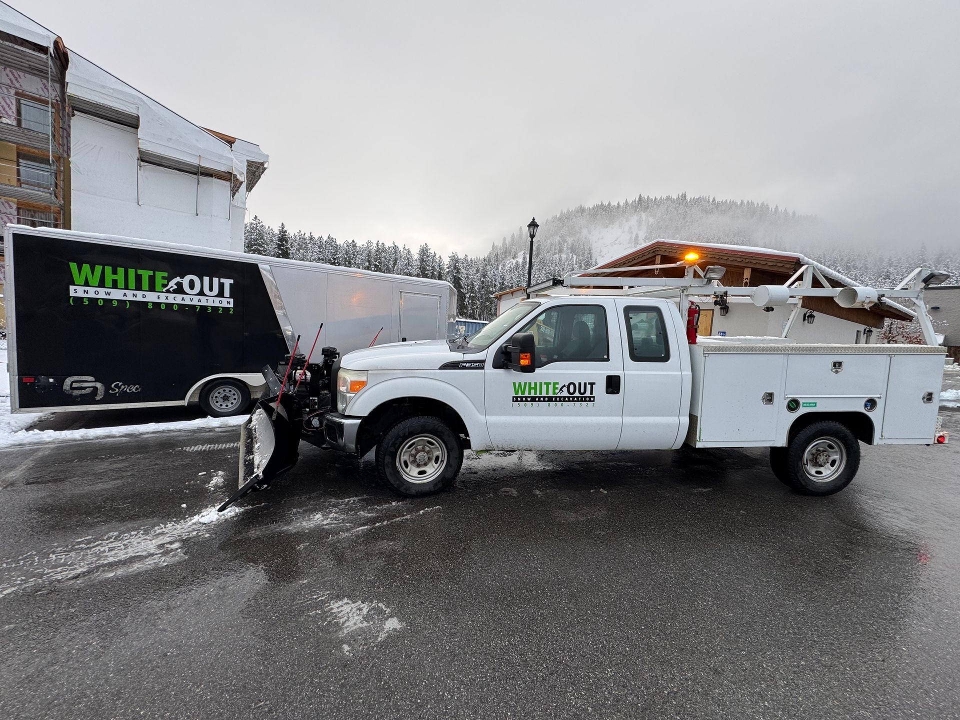A white truck with a snow plow attached to it is parked in a parking lot.
